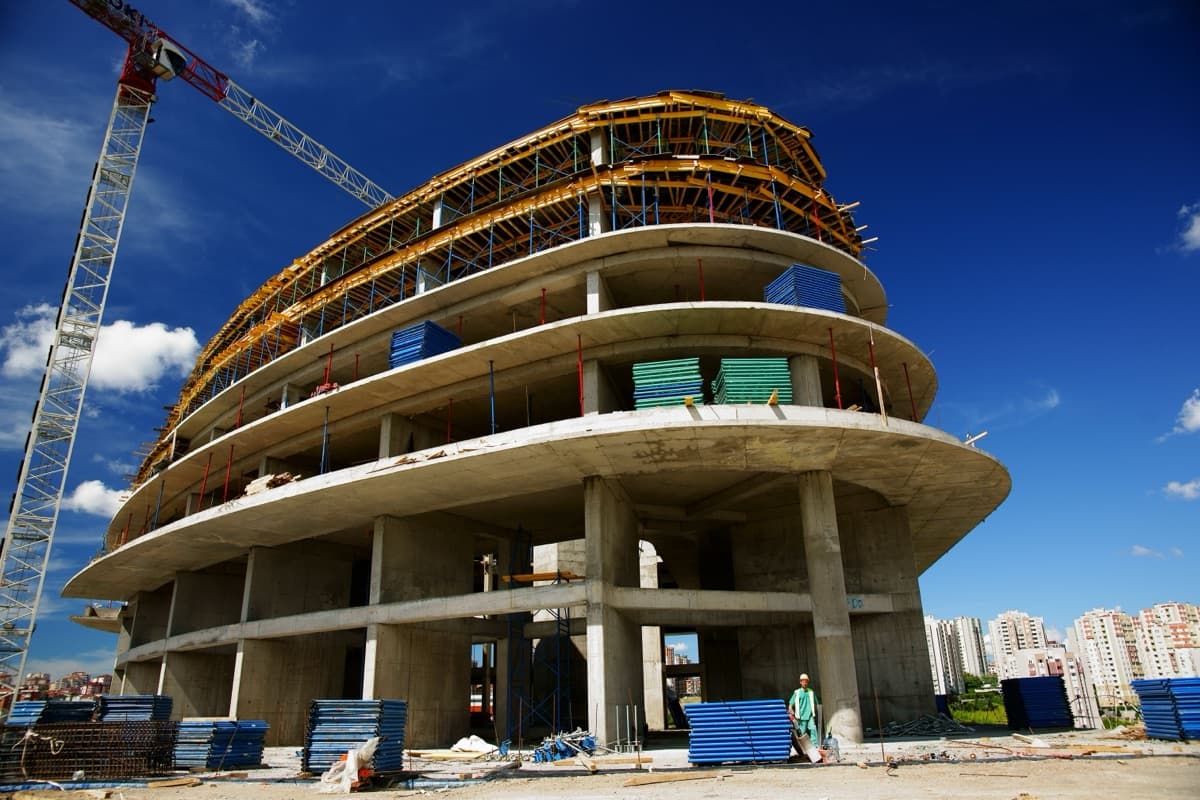 Curved multi-storey commercial building under construction beneath a tower crane